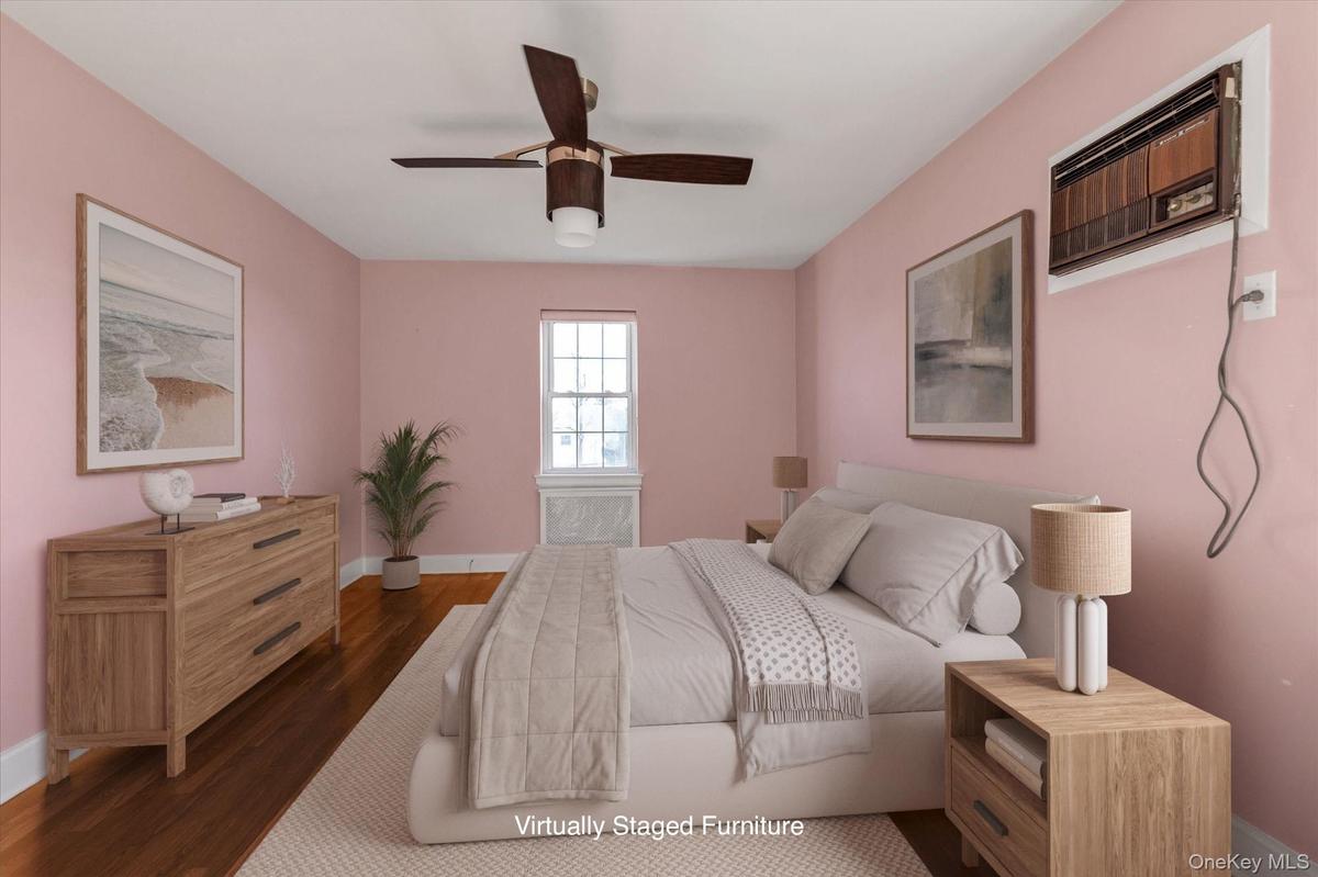 Lower level Bedroom featuring hardwood flooring, a ceiling fan with integrated lighting, a wall-mounted air conditioning unit, and a double-hung windo