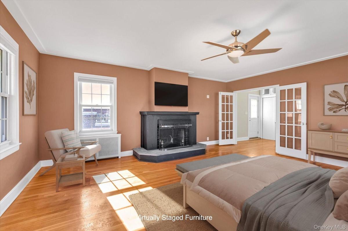 Large Primary Suite featuring hardwood flooring, a fireplace with a stone hearth, French doors. Another access door to the rooftop, and closets.