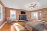 Large Primary Suite featuring hardwood flooring, a fireplace with a stone hearth, French doors. Another access door to the rooftop, and closets.