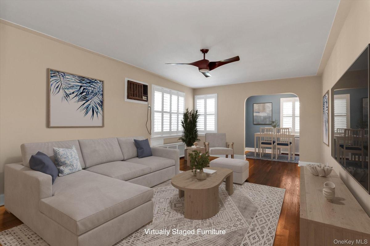 Living area featuring hard wood flooring, a ceiling fan, and white window shutters