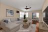 Living area featuring hard wood flooring, a ceiling fan, and white window shutters