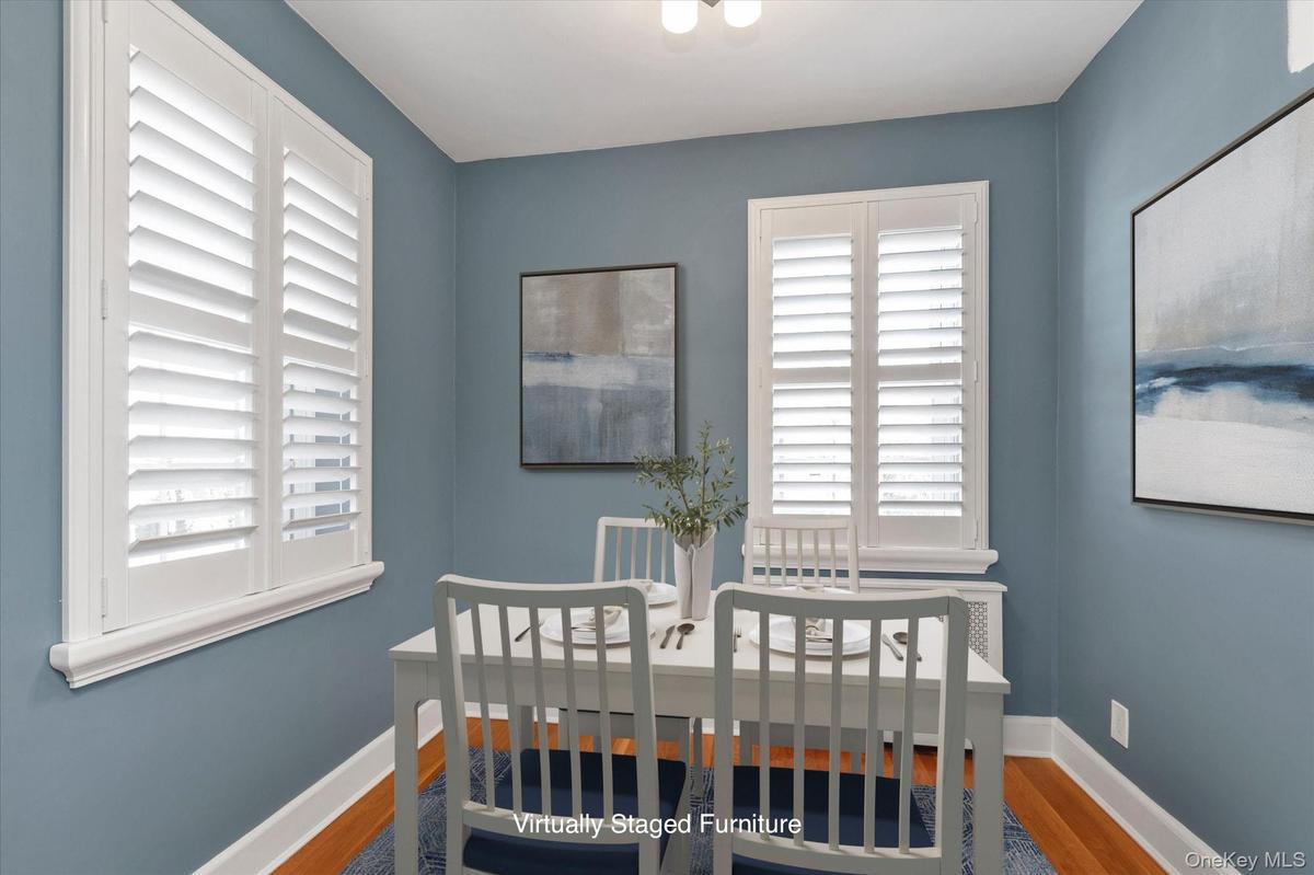 Dining Room featuring multiple windows with white plantation shutters, and hardwood flooring.