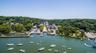 Waterfront community featuring an active marina with multiple boat slips, a paved parking area, and a tree-lined main street extending into the distan