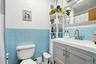 Bathroom with tile walls, vanity, wainscoting, a baseboard heating unit, and a shower with curtain