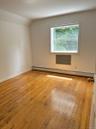 Unfurnished room featuring a baseboard heating unit, light wood-style flooring, and lofted ceiling