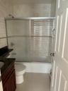 Bathroom with vanity, shower / bath combination with glass door, light tile patterned flooring, and a baseboard radiator