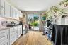 Kitchen featuring white cabinetry, light wood-type flooring, backsplash, light stone counters, and stainless steel range