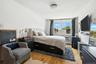 Bedroom featuring light wood-style floors, multiple windows, and baseboard heating