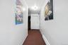 Corridor with dark colored carpet, baseboard heating, and stairway
