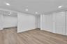 Spacious interior room featuring wood-finish flooring, recessed lighting, white walls, and multiple white bi-fold closet doors