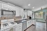 Kitchen featuring white cabinetry, granite countertops, tile backsplash, and stainless steel appliances