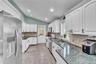 Kitchen featuring white cabinetry, dark granite countertops, stainless steel appliances, tile flooring, and a vaulted ceiling