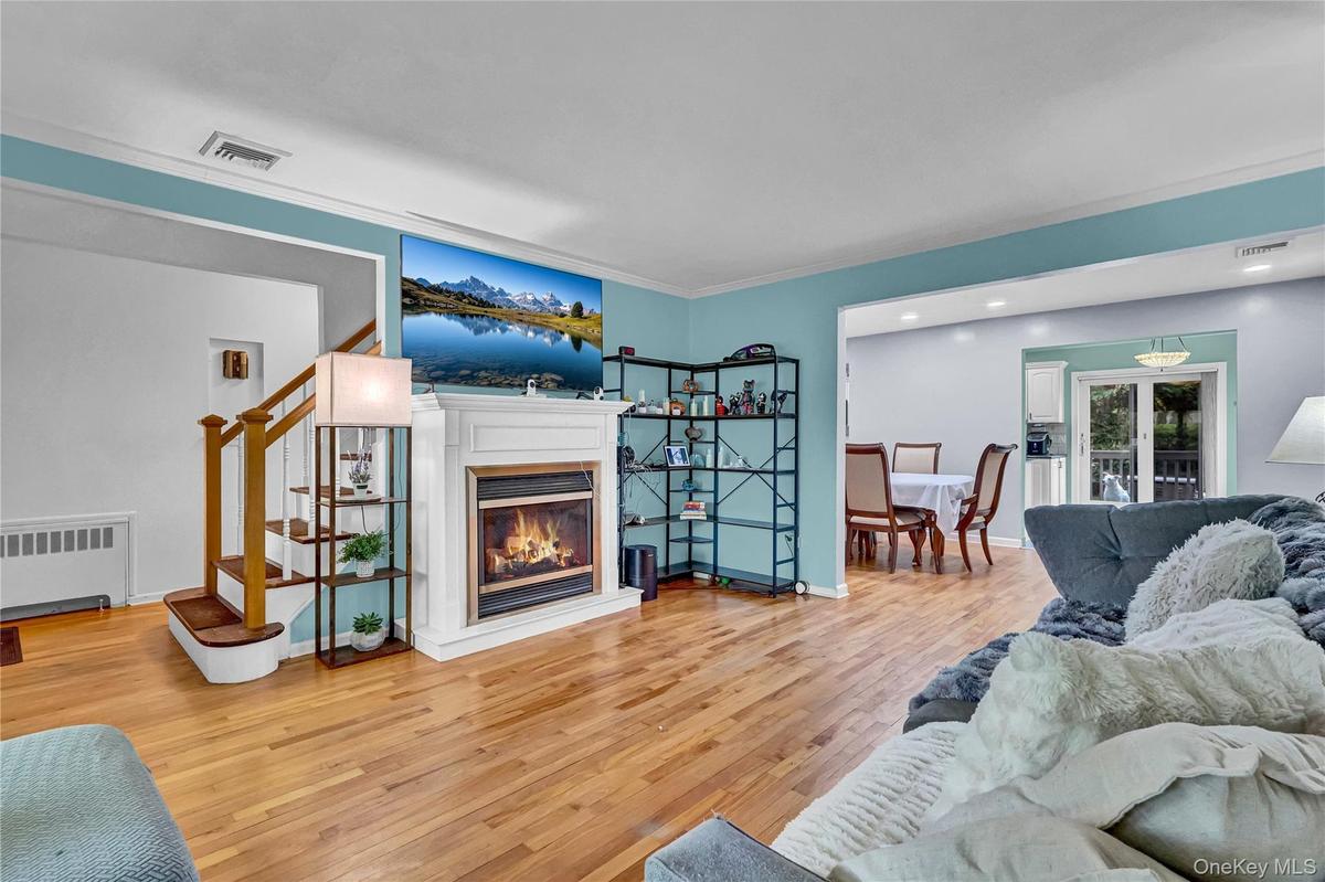 Living area featuring wood-finish flooring, a white mantel fireplace, and a light blue accent wall