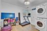 Laundry area featuring stackable washer and dryer units, wood-finish flooring, white built-in cabinetry, and a ceiling-mounted light fixture