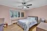 Interior room featuring a large window, a ceiling fan with integrated lighting, wood-finish flooring, and white trim accents