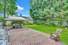 Expansive outdoor patio featuring decorative pavers, a spacious lawn, and mature perimeter trees