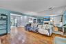 Spacious living area featuring wood-finish flooring, light blue walls, and a full wall of mirrored panels