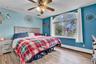 Bedroom featuring an arched window, wood-finish flooring, and a ceiling fan with integrated lighting