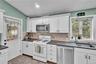 Kitchen featuring white cabinetry, dark countertops, a tile backsplash, stainless steel dishwasher, and a gas range