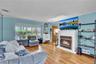 Living area featuring wood-finish flooring, a white mantel fireplace, and a large bay window