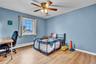 Spacious room featuring wood-finish flooring, a window with natural light, a ceiling fan with integrated lighting, and light blue wall tones