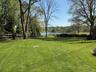 Expansive lawn featuring mature trees and a split rail fence