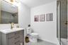Bathroom featuring a gray vanity with gold hardware, a rectangular white sink, and a gold-framed mirror