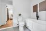 Freestanding soaking tub with matte black floor-mounted faucet, complemented by a white toilet