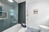 Bathroom featuring penny tile shower surround, integrated shower niche, glass shower partition, white bathtub, and built-in shelving