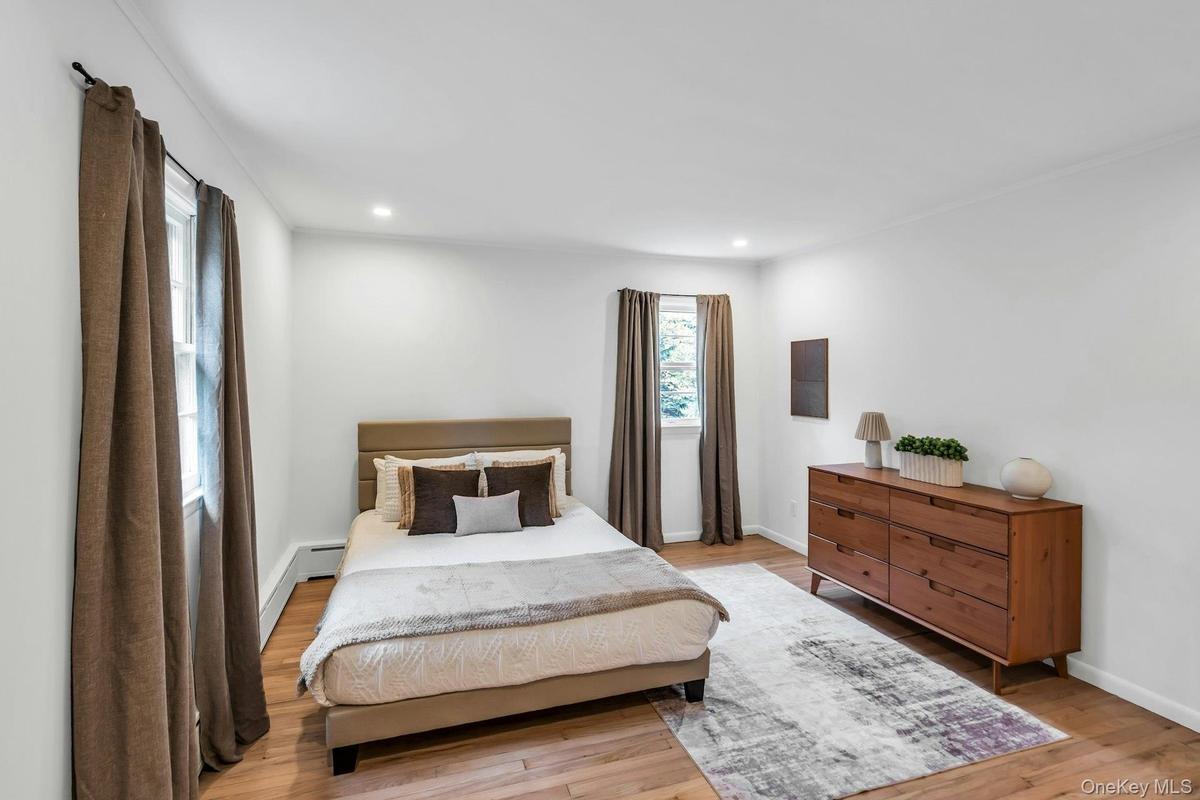 Room featuring wood-finish flooring, recessed lighting, white walls, and crown molding