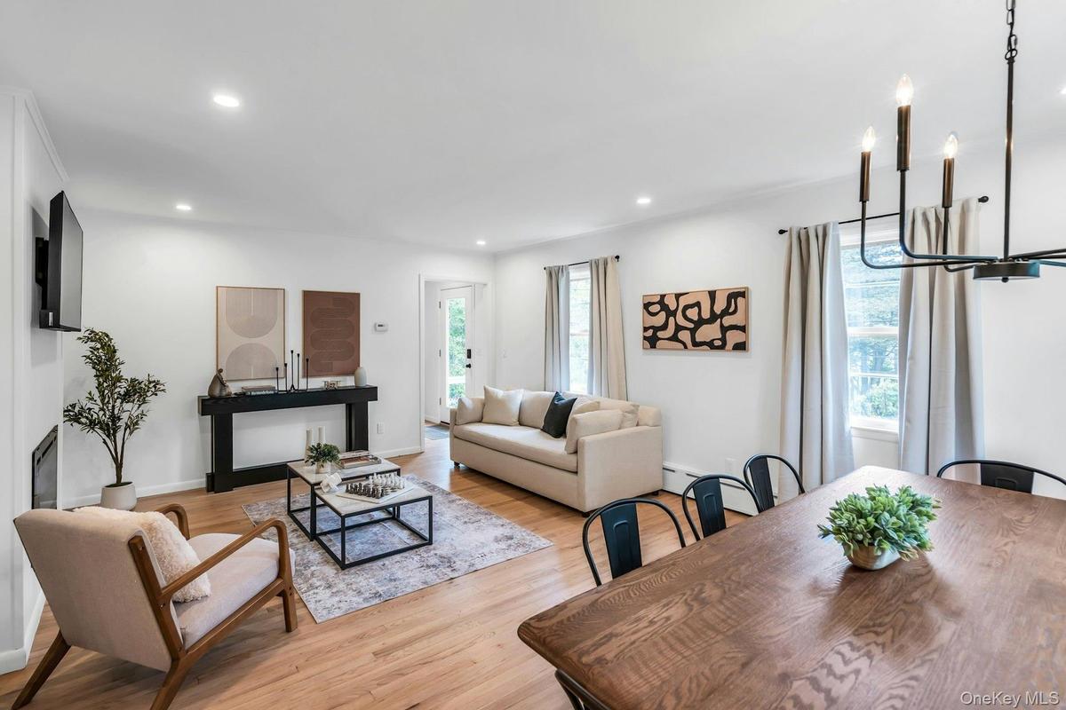 Open-concept living and dining area featuring light wood-finish flooring, recessed lighting, and a modern candelabra chandelier