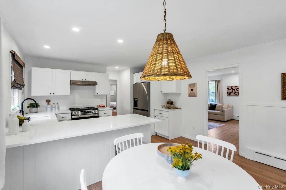 Kitchen featuring white shaker cabinetry, stainless steel appliances, recessed lighting, wood-finish flooring, and a central island with countertop se
