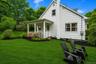 White shingle-sided home featuring a covered front porch with white railings and stone steps