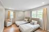 Bright room featuring warm wood-finish flooring, recessed lighting, and two windows with white trim