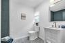 Bathroom featuring a white vanity with an undermount sink, gold-tone faucet, and a large wall mirror with integrated lighting