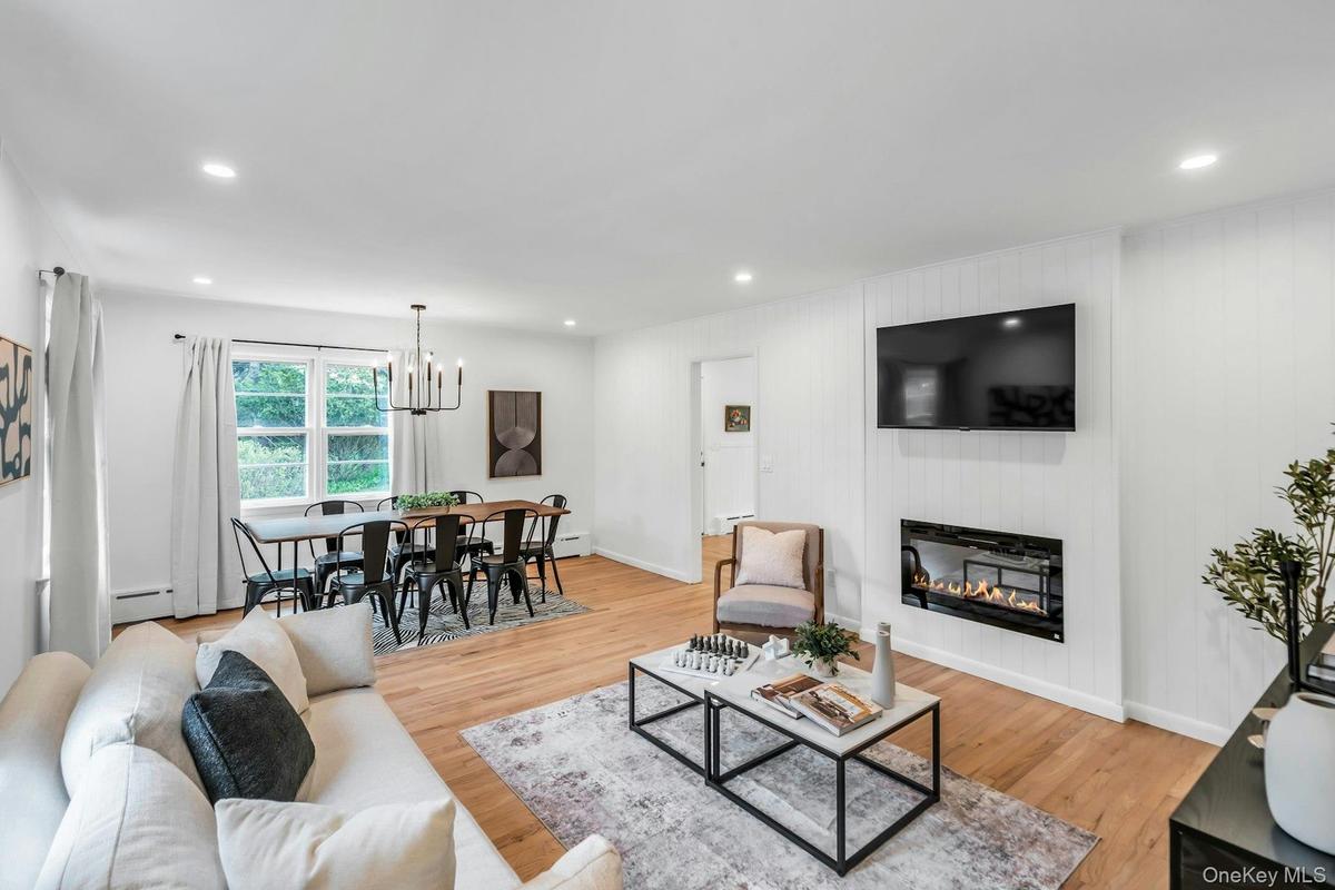 Open-concept living and dining area featuring light wood flooring, recessed lighting, a built-in linear electric fireplace, and a dining space with a 