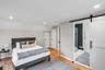 Wood-finish flooring throughout, featuring recessed ceiling lighting, a white barn door on a black rail system, and neutral wall paint
