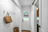 Entryway featuring white shiplap walls with black hooks, a glass-paned door, wood-finish flooring, and a black barn door track