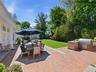 Brick patio with outdoor kitchen, dining area, and lush yard.