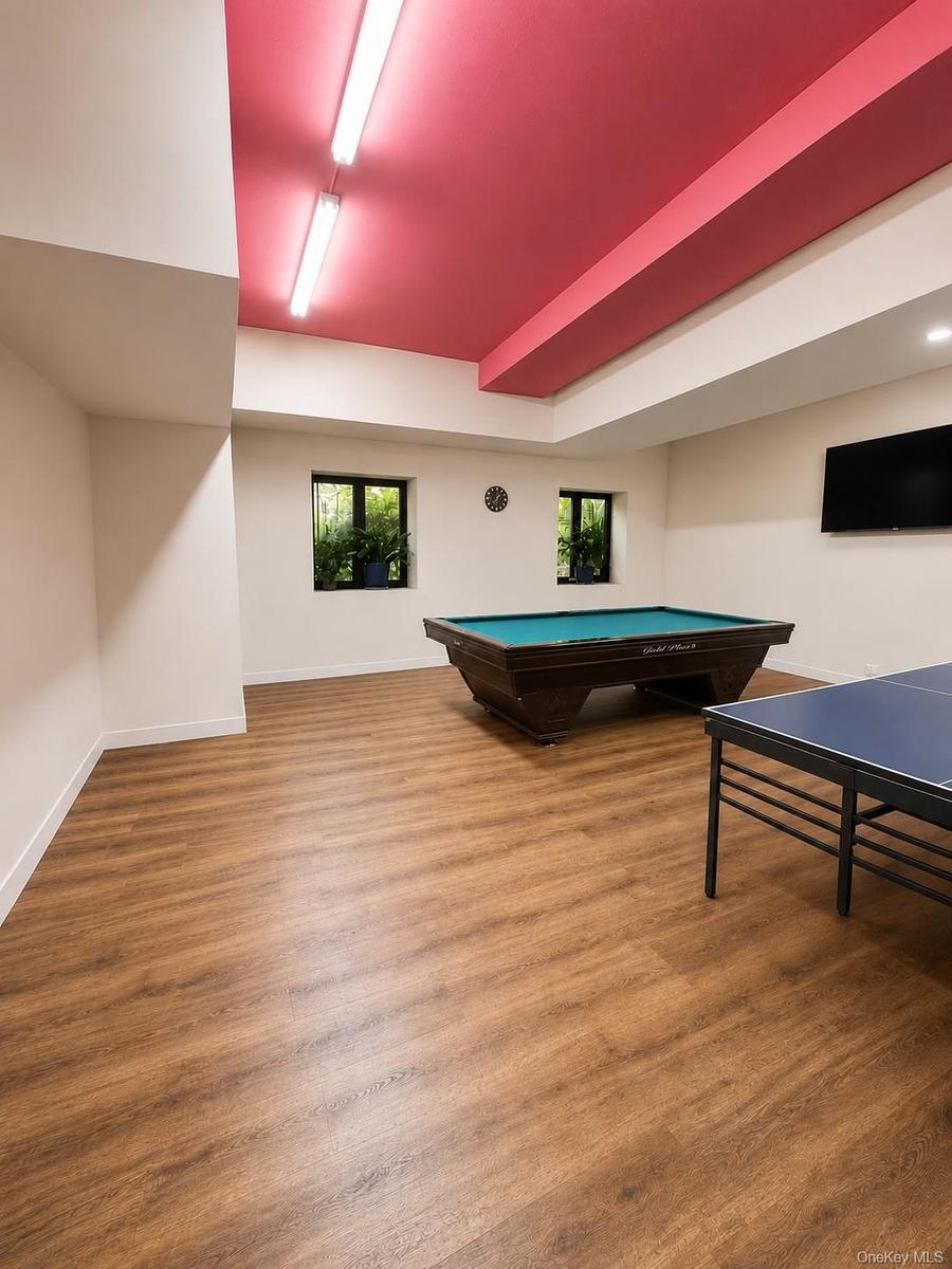 Spacious interior with wood-finish flooring and a distinctive red ceiling featuring exposed ductwork