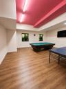 Spacious interior with wood-finish flooring and a distinctive red ceiling featuring exposed ductwork