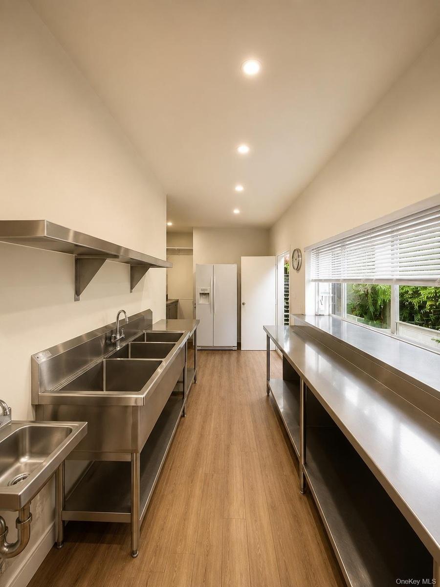 Commercial kitchen space featuring wood-finish flooring, recessed lighting, and stainless steel countertops