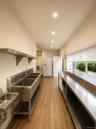 Commercial kitchen space featuring wood-finish flooring, recessed lighting, and stainless steel countertops