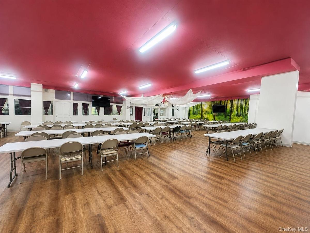 Expansive open-plan commercial space featuring wood-finish flooring, a painted ceiling, and fluorescent lighting