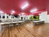 Expansive open-plan commercial space featuring wood-finish flooring, a painted ceiling, and fluorescent lighting
