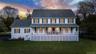 Classic colonial-style residence featuring white siding and dark green shutters