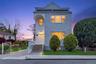Two-story residence featuring light-colored siding, a prominent front entrance with a decorative door, and a concrete pathway leading to steps with wh