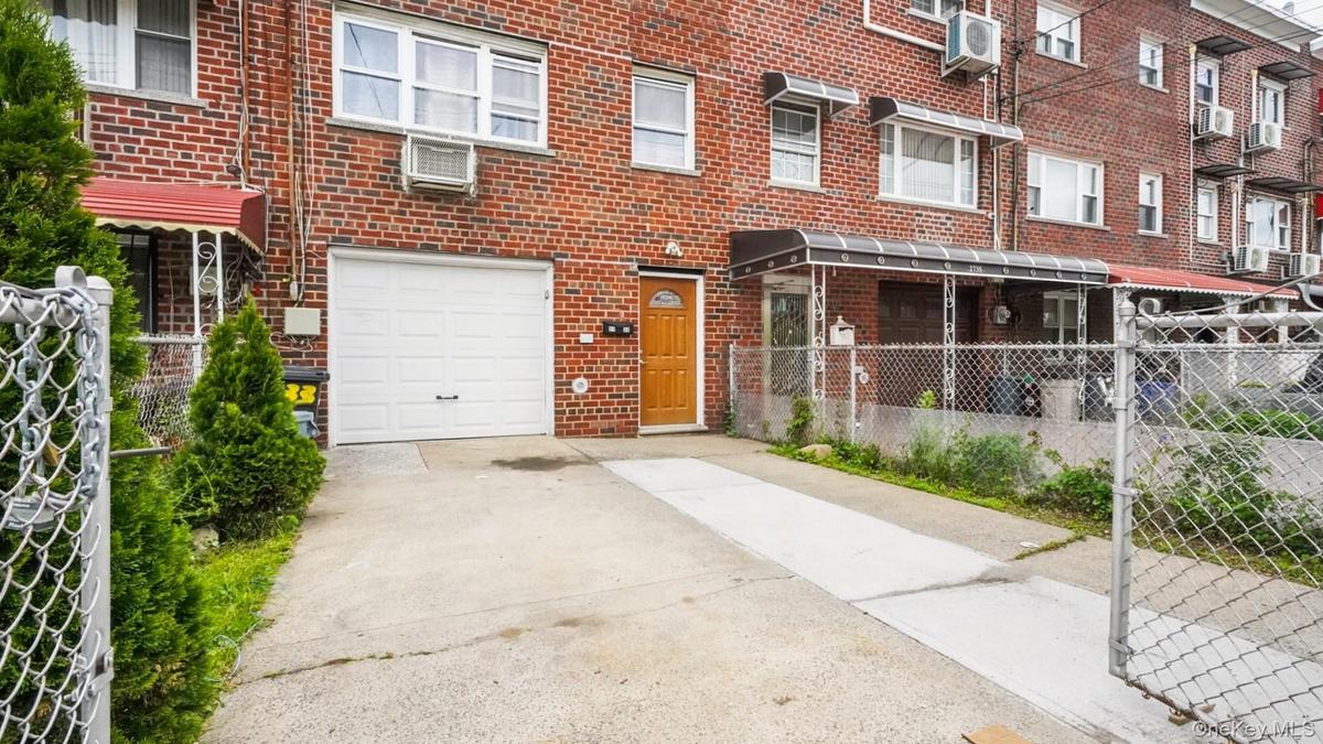 Brick facade residence featuring a white garage door, concrete driveway, and covered front entry
