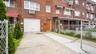 Brick facade residence featuring a white garage door, concrete driveway, and covered front entry