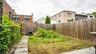 Expansive fenced backyard featuring a concrete patio section, a stone paver pathway, and mature perimeter foliage